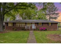 Charming brick home featuring a well-maintained lawn and mature trees, providing shade and curb appeal at 1903 Kirkwood Dr, Durham, NC 27705