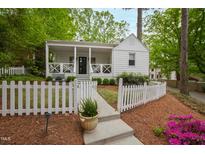 Charming cottage-style home featuring a welcoming front porch and a picket fence lined with colorful flowerbeds at 2415 Van Dyke Ave, Raleigh, NC 27607