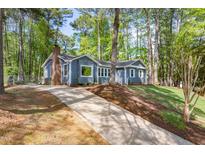 Charming blue home featuring a brick chimney, lush trees, and a long driveway at 403 Mayodan Dr, Cary, NC 27511