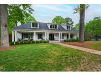 Inviting white brick home with a covered front porch and manicured lawn, creating a warm and welcoming curb appeal at 4237 Rowan St, Raleigh, NC 27609