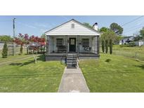 Charming single story home featuring a cozy front porch, beautiful lawn, and an inviting walkway at 729 S Carolina Ave, Henderson, NC 27536