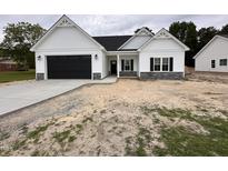Charming single-story home featuring a black garage door, stone accents, and a well-manicured lawn at 1008 Peedin Rd, Selma, NC 27576