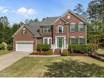Charming two-story red brick home with a well-manicured lawn, complemented by lush greenery and colorful flowerbeds at 112 Natchez Ct, Cary, NC 27519