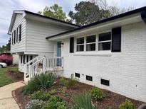 Beautifully landscaped white brick home with a charming blue front door and black shutters at 3713 Arrowwood Dr, Raleigh, NC 27604