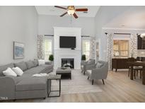 Bright living room with fireplace, large sectional sofa, accent chairs, and hardwood floors at 8021 Crookneck Dr, Angier, NC 27501