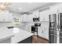 Bright kitchen features white cabinetry, stainless steel appliances, granite countertops, and hardwood flooring at 105 Blooms Way, Kenly, NC 27542