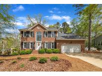 Brick two-story home featuring a well-manicured front yard, black shutters, and an attached two-car garage at 1100 Queensbury Cir, Durham, NC 27713