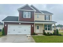 New two-story home featuring a two-car garage, red and beige siding, and a well-manicured front lawn at 120 W Saltgrass Ln, Smithfield, NC 27577