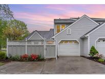 Charming home featuring gray siding, white garage door, and tasteful landscaping at sunset at 201 Lakewater Dr, Cary, NC 27511