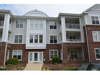 Three-story condo building with brick facade and multiple balconies, complemented by vibrant landscaping at 224 Eyam Hall Ln, Apex, NC 27502