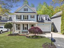 Charming two-story home featuring a covered front porch, well-manicured lawn, and attached two-car garage at 301 Marsh Landing Dr, Holly Springs, NC 27540