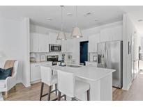 Bright, eat-in kitchen features stainless appliances, white cabinets, a center island with seating, and pendant lights at 3667 Durwood Ln, Raleigh, NC 27604