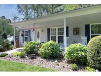 Inviting home featuring a covered front porch, trimmed landscaping, and a charming entrance with decorative accents at 38 Maple Cir, Pittsboro, NC 27312