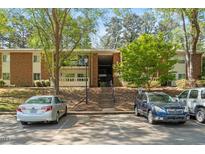Brick building with parking lot, mature trees, and stairwell entrance at 4507 Edwards Mill Rd # F, Raleigh, NC 27612