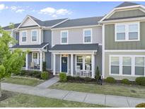 Charming townhome with a blue front door, rocking chairs on the porch and well-maintained landscaping at 6511 Academic Ave, Raleigh, NC 27616