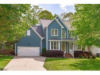 Charming two-story home with a well-manicured lawn, blue siding, and an attached two-car garage at 8005 Somerdale Dr, Durham, NC 27713