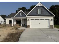 Charming home featuring a two-car garage, gray accents, a manicured lawn, and a welcoming entrance at 1000 Peedin Rd, Selma, NC 27576