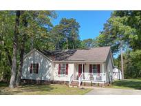 Charming single-story home featuring red shutters, a covered porch, and lush surrounding trees at 334 Cabin Grove Ct, Angier, NC 27501