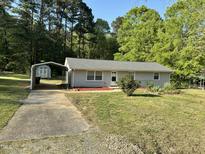 Charming single-story home with a carport and landscaped front yard surrounded by mature trees at 3815 Weyburn Rd, Durham, NC 27704