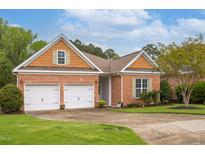 Charming home with brick exterior, two-car garage, manicured lawn, and cedar shake accents at 4 Calwell Creek Dr, Chapel Hill, NC 27517