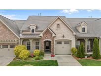 Charming home exterior featuring stone and brick accents, a two-car garage, and professionally landscaped front yard at 4105 Gilchrist Dr, Burlington, NC 27215