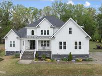 Charming two-story white farmhouse with black accents, manicured lawn, and inviting front porch at 6024 Lunenburg Dr, Raleigh, NC 27603