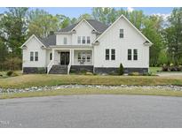 Charming white two-story home with stone accents, covered porch, and well-manicured lawn at 6024 Lunenburg Dr, Raleigh, NC 27603