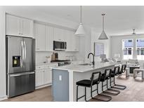 Modern kitchen boasts stainless appliances, a large island with seating, and white cabinets at 6406 Tanner Oak Ln, Raleigh, NC 27613