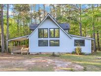 Charming light blue home with a covered porch, offering a glimpse into the tranquil wooded surroundings at 924 Lynn Rd, Durham, NC 27703