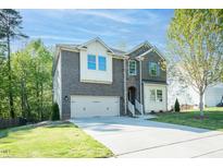 Charming two-story brick home with attached garage, and manicured lawn on a sunny day at 1004 Longleaf Pine Pl, Mebane, NC 27302