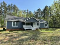 Charming home with blue siding, white trim, and a welcoming front porch set against a backdrop of mature trees at 1010 Pool Rock Rd, Henderson, NC 27537