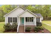 Charming home featuring a quaint front porch, a teal door, and meticulously landscaped garden beds at 1106 Lake Ridge Dr, Creedmoor, NC 27522