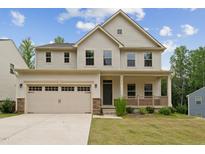 Two-story home with a large front lawn, a two-car garage, and a cozy porch at 1216 Edgemoore Trl, Wake Forest, NC 27587