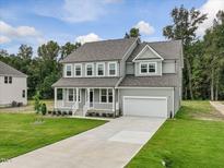Two-story home featuring a welcoming front porch, attached garage, and well-manicured lawn at 138 Alden Way, Angier, NC 27501
