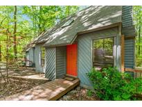 Charming home exterior featuring a modern gray facade, orange front door, and wooden walkway in a wooded setting at 158 Poplar St # A, Chapel Hill, NC 27516
