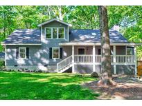 Charming gray home featuring a covered porch, black shutters, and a lush green lawn with mature trees at 1715 Us 15-501 S, Chapel Hill, NC 27517