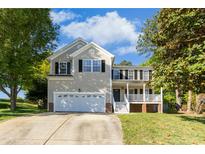 Charming two-story home with a front-facing two-car garage, well-manicured lawn, and mature trees at 213 Meadow Fox Rd, Holly Springs, NC 27540