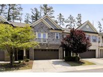 Charming townhome featuring a stone and brick facade, two-car garage, and well-manicured landscaping at 317 Castle Rock Ln, Cary, NC 27519