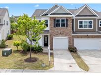 Charming townhome with stone facade and attached garage, complemented by a well-manicured lawn and young tree at 5518 Jessip St, Morrisville, NC 27560