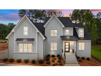 Inviting two-story home with light-gray painted brick, black accents, and manicured landscaping creates eye-catching curb appeal at 7301 Wexford Woods Ln, Wake Forest, NC 27587