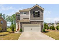 Two-story home with stone and gray siding, a two-car garage, and a well-manicured lawn at 1036 S Fieldhaven Dr, Fuquay Varina, NC 27526