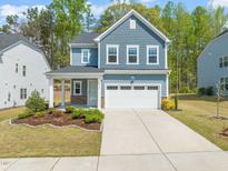 Charming two-story home with blue siding, white trim, a well-manicured lawn, and a two-car garage at 1120 Copper Beech Ln, Wake Forest, NC 27587