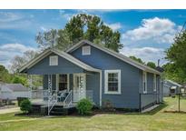 Charming blue single-story home featuring a welcoming front porch, landscaped yard, and mature trees at 1542 Albright Ave, Burlington, NC 27215
