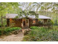 Charming home exterior with wood siding, metal roof, and beautifully landscaped front yard at 195 Nicks W Bnd, Pittsboro, NC 27312