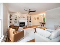 Bright living room with a fireplace, built-in shelving, plush rug, and wood flooring at 3317 E Jameson Rd, Raleigh, NC 27604