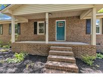 Charming brick home featuring a covered front porch with a vibrant blue front door and classic black shutters at 419 Joy Dr, Garner, NC 27529