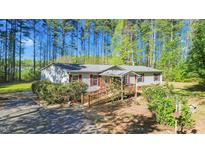 Charming one-story home features a sloped wooden ramp, complemented by lush landscaping and tall trees at 4500 Governor Hunt St, Efland, NC 27243