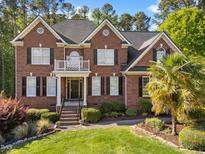 Beautiful two-story brick home featuring a balcony, manicured lawn, and mature landscaping at 5016 Dillswood Ln, Raleigh, NC 27606