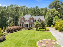 Stately brick home with a manicured lawn and mature trees creating a picturesque setting at 5016 Dillswood Ln, Raleigh, NC 27606