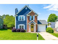 Charming two-story home with blue siding, brick accents, a well-manicured lawn, and a welcoming yellow front door at 909 Starkland Way, Holly Springs, NC 27540